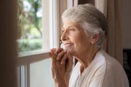 Happy senior woman looking out a window