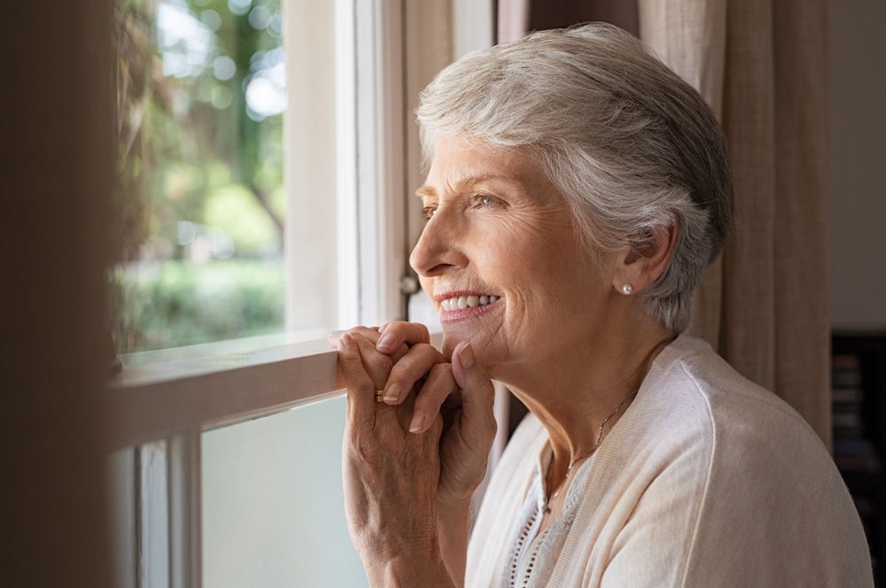 Happy senior woman looking out a window